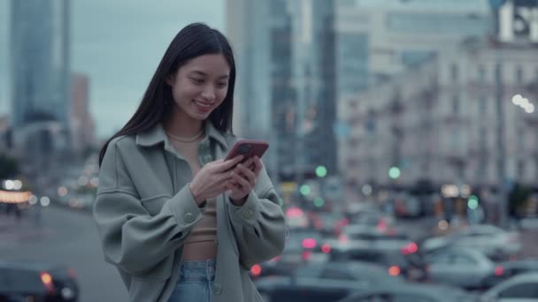 Wanita asia Positif SMS di smartphone luar ruangan — Stok Video