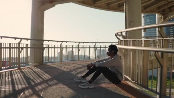 街の橋でリラックスしたアフリカ系アメリカ人の女性ランナー — ストック動画