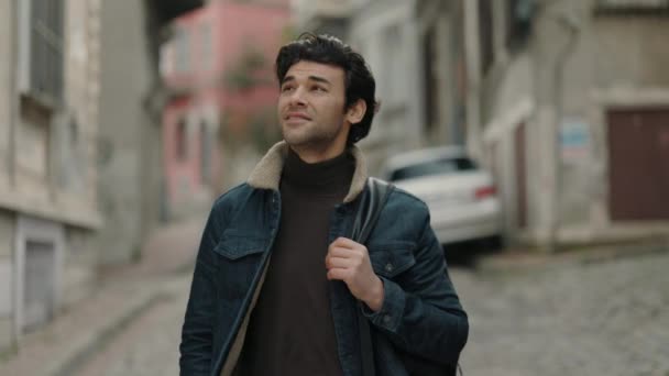 Şehir caddesinde yürüyen ve sırt çantası taşıyan yakışıklı bir adam. — Stok video