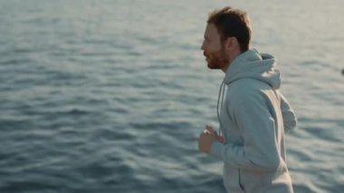 Sakallı erkek sporcu. Nehir kenarında koşuyor.