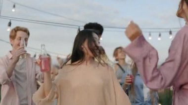 Asyalı kadın çatıda çok ırklı arkadaşlarıyla dans ediyor.