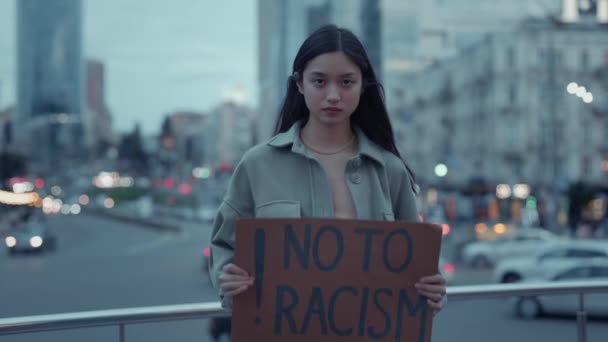 Азиатка держит картон с лозунгом "нет расизму" — стоковое видео