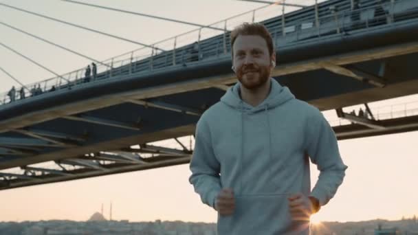 Hombre corriendo al aire libre y usando reloj inteligente con auriculares — Vídeo de stock