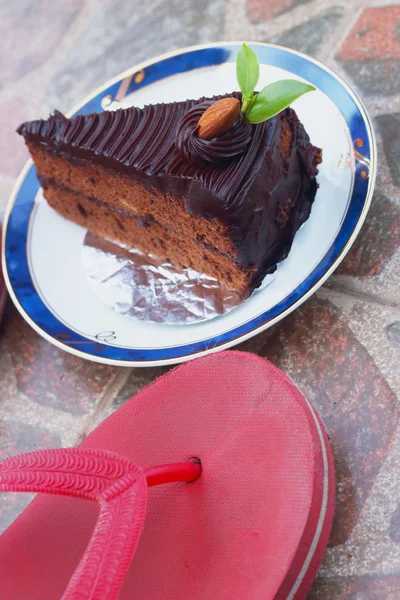 Chocolate cake and red rubber shoes. — Stock Photo, Image