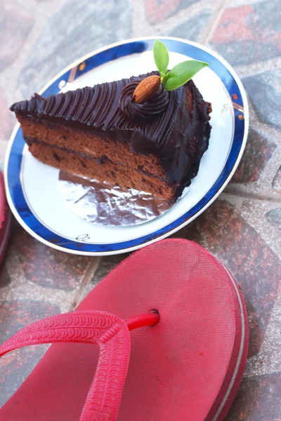 Chocolate cake and red rubber shoes. — Stock Photo, Image