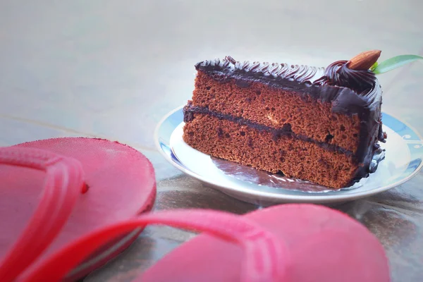 Chocolate cake and red rubber shoes. — Stock Photo, Image