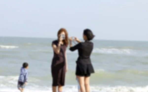 Mujer borrosa usando una cámara en la playa . —  Fotos de Stock