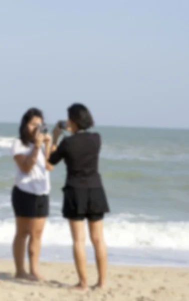 模糊的女人在沙滩上使用相机. — 图库照片
