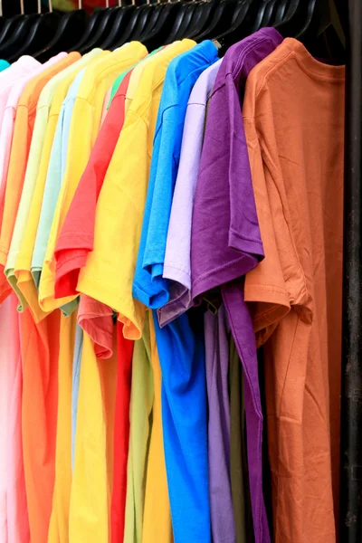Loja camisas colorido tecido pendurado em um rack . — Fotografia de Stock