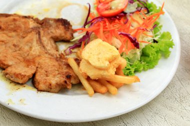 Domuz pirzolası, kızarmış patates salatası ile