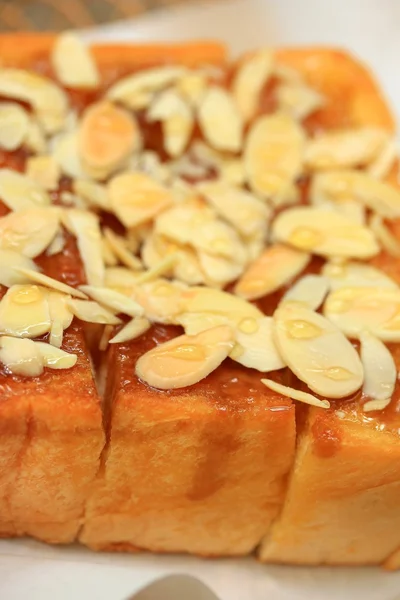 Toast brood gegarneerd met honing en amandel. — Stockfoto