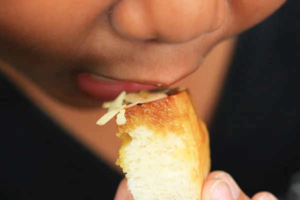 Ragazzo mangiare pane tostato condito con miele e mandorle . — Foto Stock