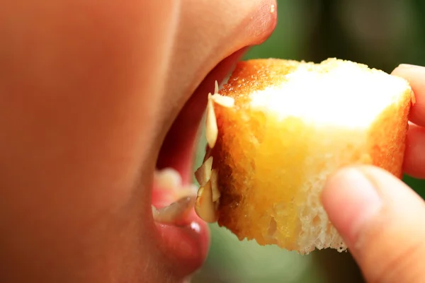 Niño comiendo pan tostado cubierto con miel y almendras . —  Fotos de Stock