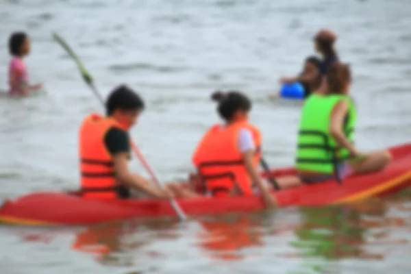 Verschwommene Menschen spielen Boot Gummi auf See — Stockfoto