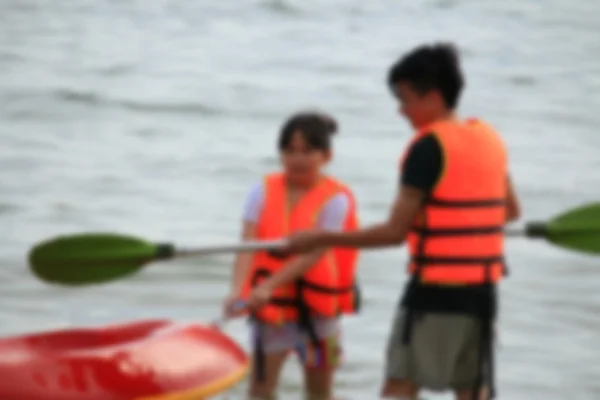 Wazig mensen spelen boot rubber op zee — Stockfoto