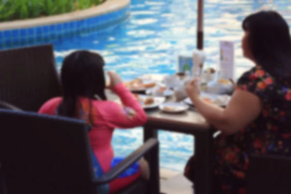 Personas borrosas comiendo junto a la piscina — Foto de Stock