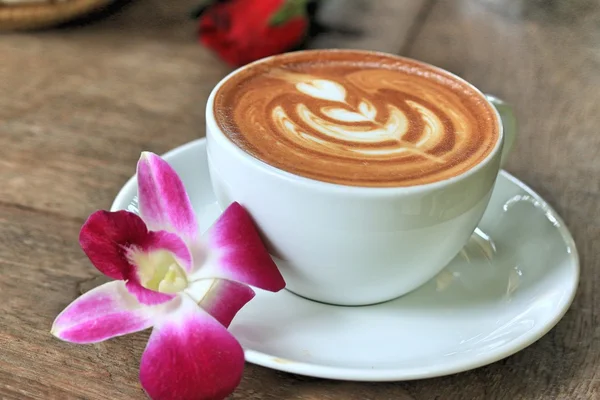Vintage latte art coffee and pink orchid — Stock Photo, Image