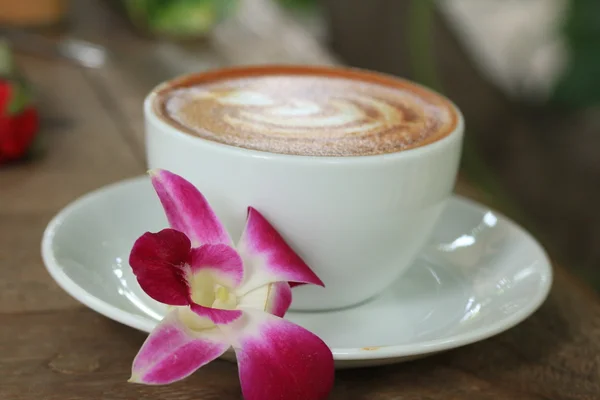 Vintage latte art coffee and pink orchid — Stock Photo, Image