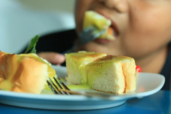 Kinderen eten toast gegarneerd met vla en slagroom. — Stockfoto