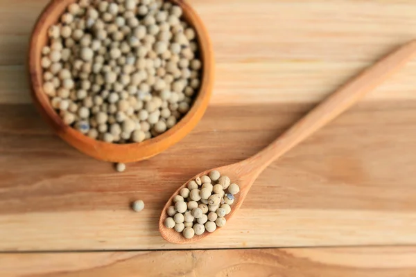 White pepper seeds on wooden background. — Stock Photo, Image