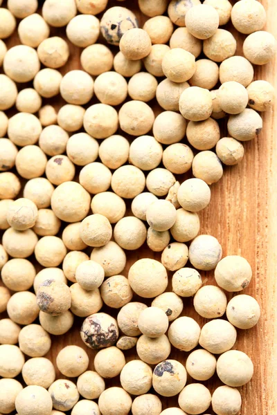 Semillas de pimienta blanca sobre fondo de madera . — Foto de Stock