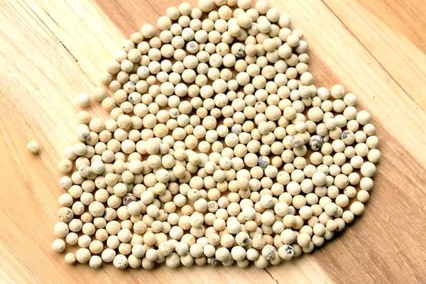 White pepper seeds on wooden background. — Stock Photo, Image