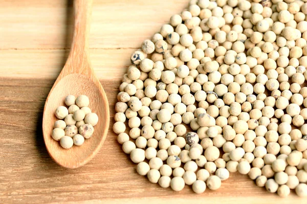 Bílý pepř semen na dřevěné pozadí. — Stock fotografie