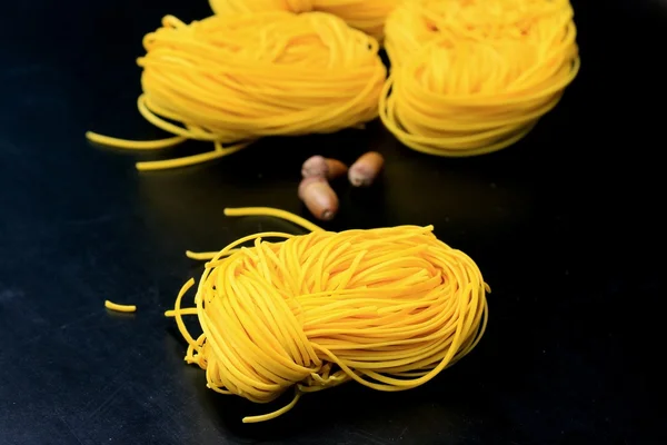 Yellow noodles drying on black background — Stock Photo, Image
