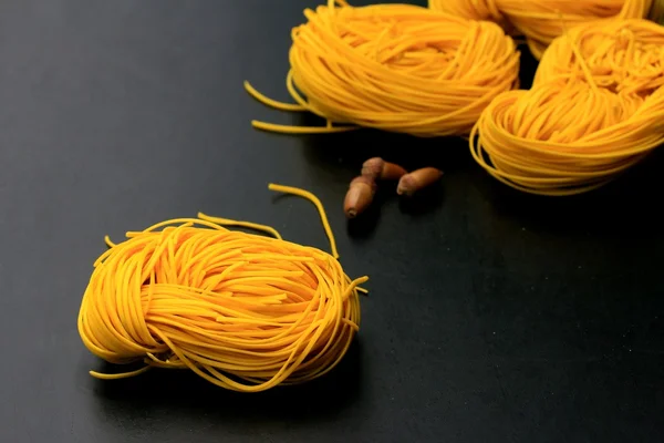 Macarrão amarelo secagem no fundo preto — Fotografia de Stock