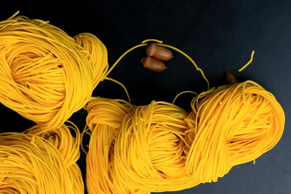 Macarrão amarelo secagem no fundo preto — Fotografia de Stock