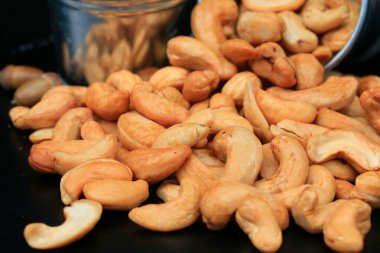 yığın kaju fıstığı ve siyah arka plan üzerine tuz