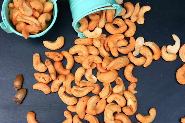 Heap cashew nuts and salt on black background — Stock Photo, Image