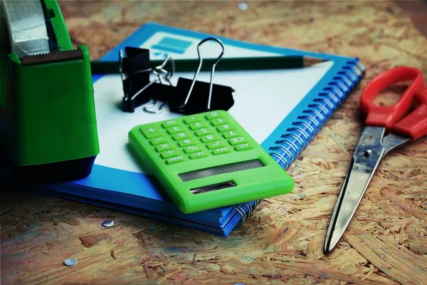 Mélanger livre et calculatrice, agrafeuse, ruban adhésif, poinçon de papier, crayon — Photo