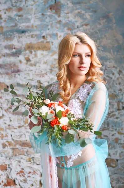 Charming young blond woman holding fresh flowers