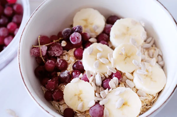 Gesundes Frühstück. Haferflocken mit Bananen, Preiselbeeren und Sonnenblumen — Stockfoto