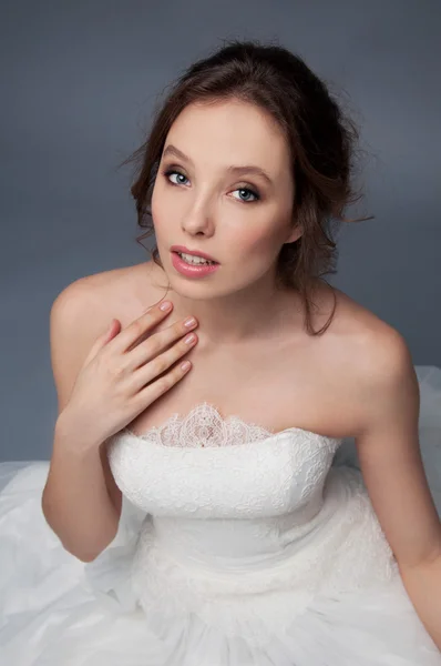 Adorabile giovane sposa con capelli castani ricci seduta in una nuvola di — Foto Stock