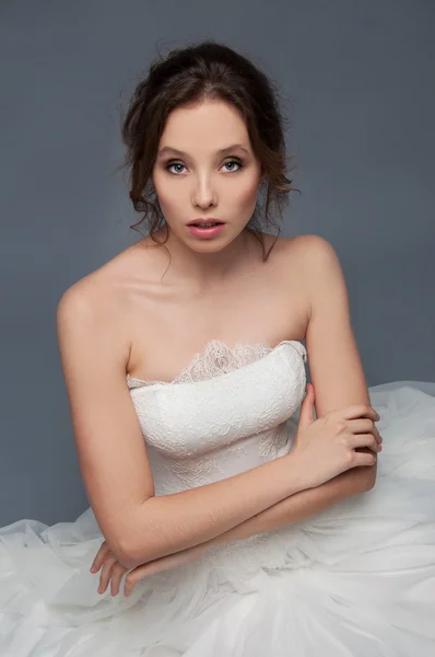 Adorabile giovane sposa con capelli castani ricci seduta in una nuvola di — Foto Stock