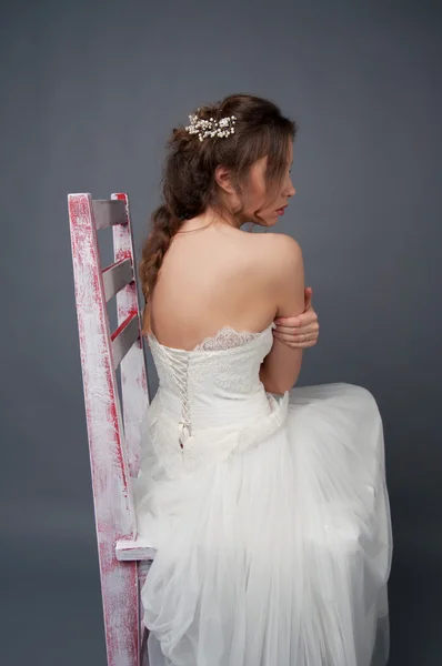 Молодая невеста сидит одна на стуле в свадебном платье — стоковое фото