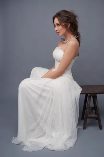 Panna Młoda w biały ślub sukienka sitiing na ławce — Zdjęcie stockowe