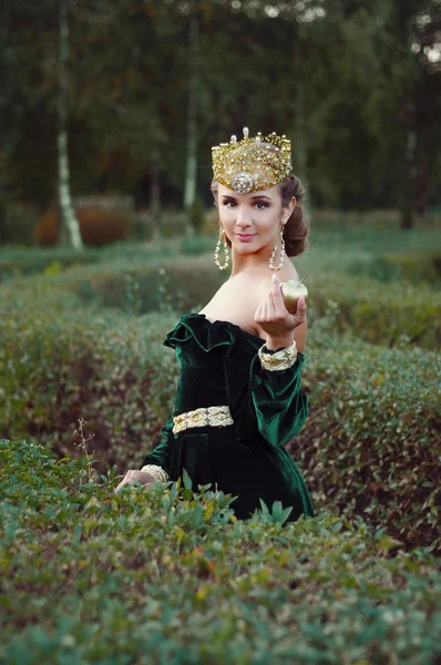 Elegante jovem mulher vestida como rainha andando no jardim — Fotografia de Stock