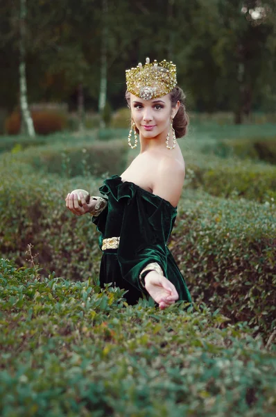 Elegante jovem mulher vestida como rainha andando no jardim — Fotografia de Stock