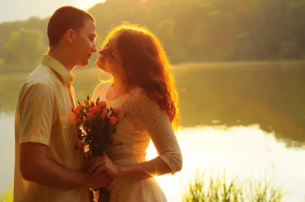 Casal de jovens amantes abraçando a luz do pôr do sol — Fotografia de Stock