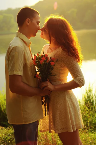 Casal de jovens amantes abraçando a luz do pôr do sol — Fotografia de Stock