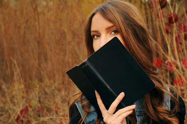 Linda joven en el bosque de otoño leyendo un libro — Foto de Stock