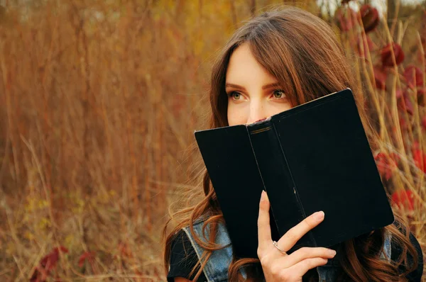 Carina giovane donna nella foresta autunnale a leggere un libro — Foto Stock