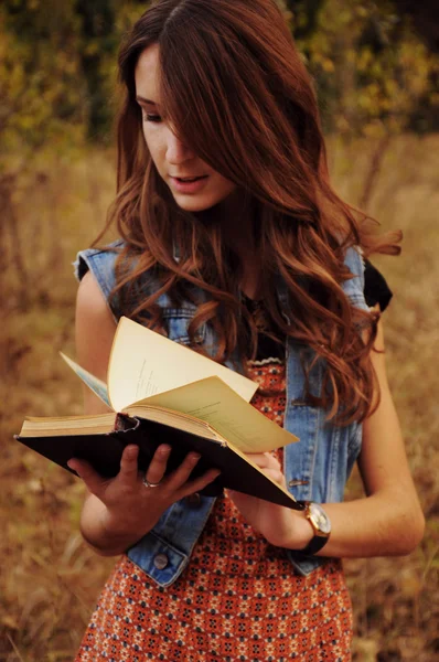 Mulher jovem bonito na floresta de outono lendo um livro — Fotografia de Stock