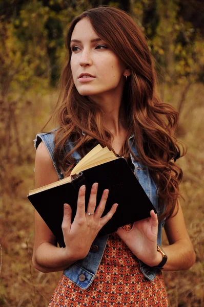 Linda joven en el bosque de otoño leyendo un libro — Foto de Stock
