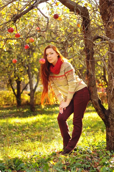 Mujer pelirroja joven con el pelo largo y liso en la garde de la manzana — Foto de Stock