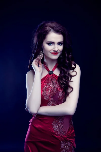 Beautiful redheaded woman with long curly hair in red evening dr — Stock Photo, Image