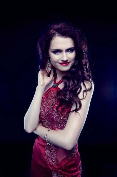 Beautiful redheaded woman with long curly hair in red evening dr — Stock Photo, Image